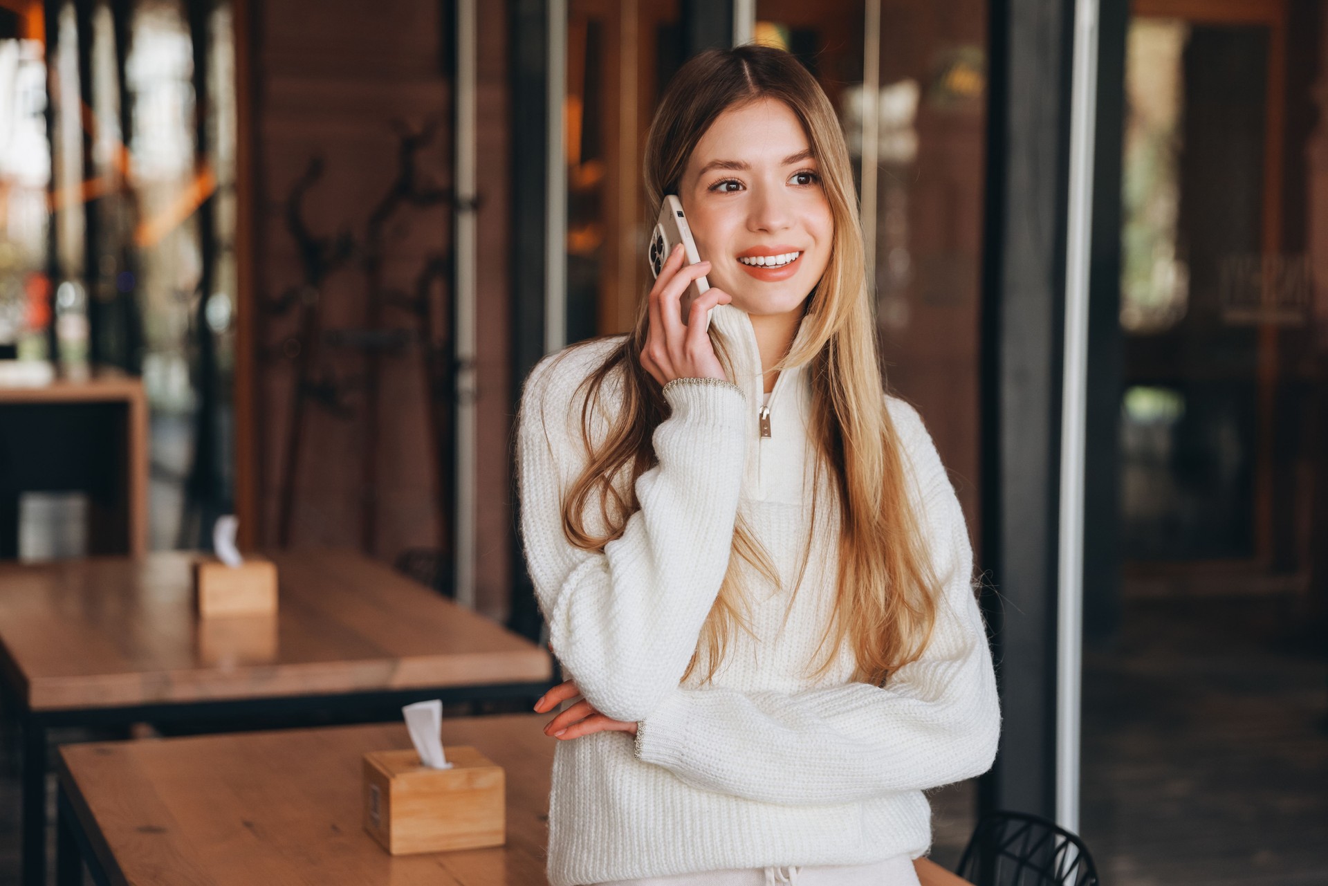 Smiling blonde woman making a phone call in a cafe