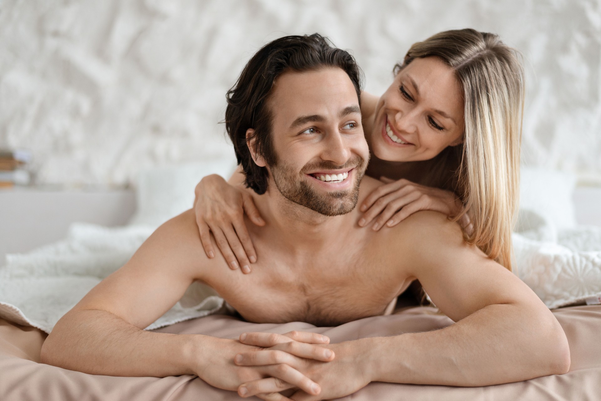 Affectionate caucasian couple lying together in bed after lovemaking, lovers relaxing and cuddling after having sex