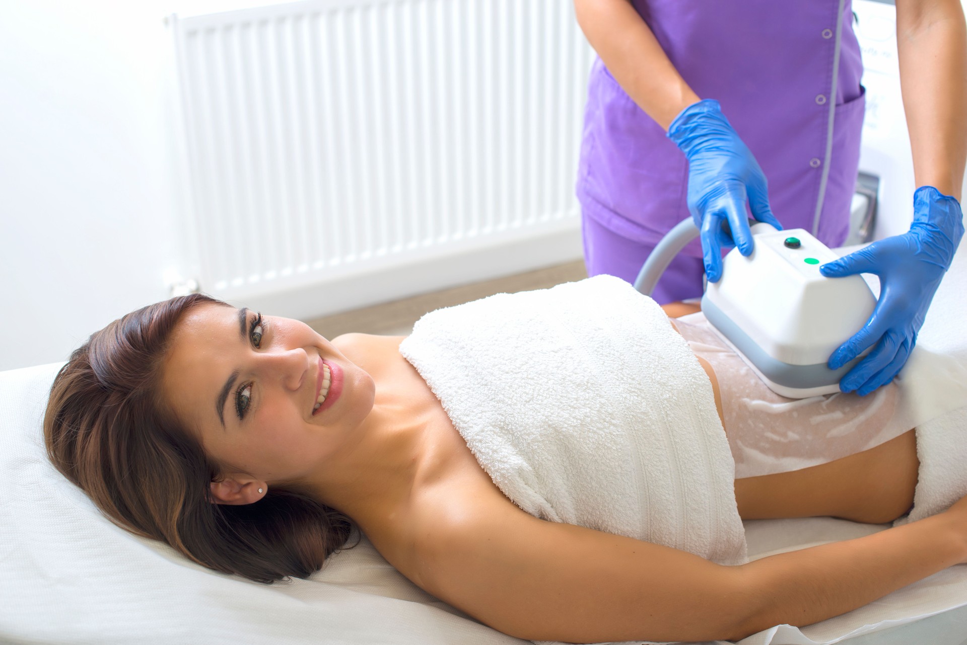 Pretty young woman getting cryolipolyse treatment in cosmetic cabinet