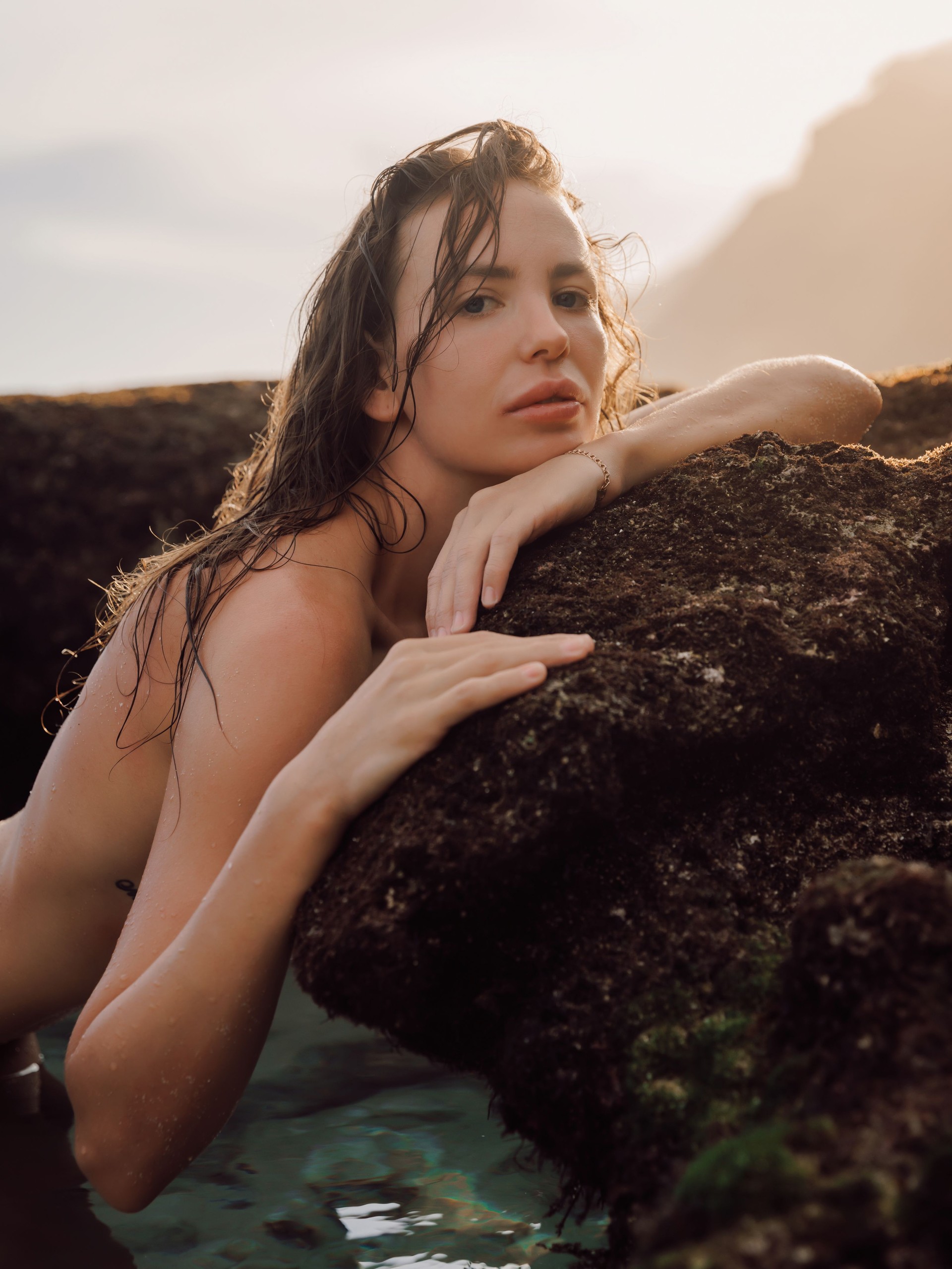 Portrait of attractive woman with tanned body on ocean beach. Beauty lady look at camera in water with warm sunlight